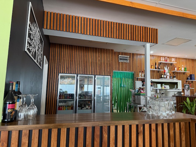 Wooden bar counter at Little Spicy with glass stemware and a bottle display