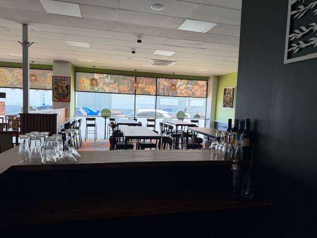 View across the bar towards the window, with high tables and daylight