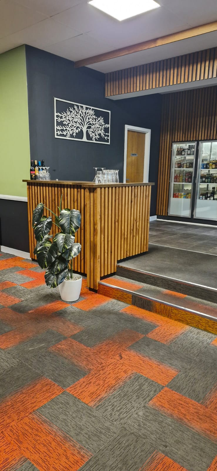Entry and host stand at Little Spicy with a timber tree artwork on a charcoal wall